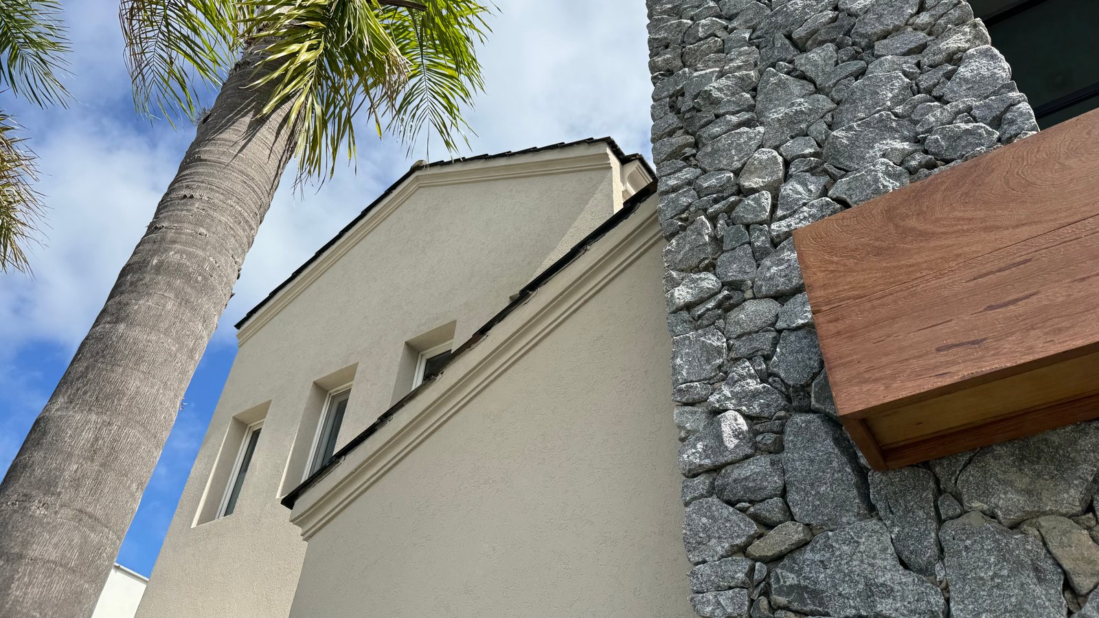 Fachada moderna con estuco blanco y detalles en piedra — proyecto CASA CM, por Hermann Arquitectos, en Los Castores